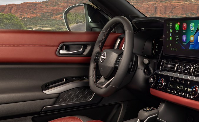 Interior de SUV con tapicería negra y borgoña, pantalla central y consola, visto desde el asiento del pasajero.