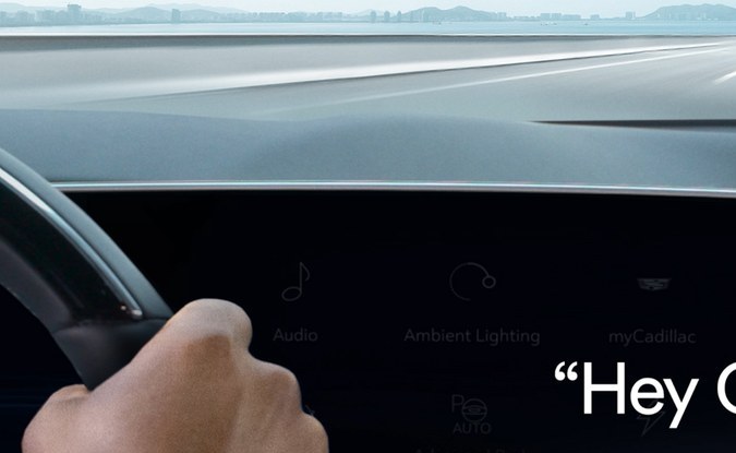 Mano sobre el volante frente a una pantalla curva del tablero que muestra el mensaje Hey OnStar.