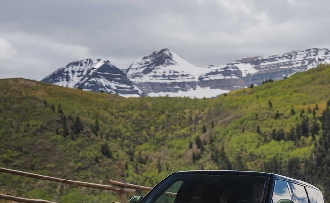 Dos SUV Rivian R2, una verde y una blanca, circulando por una carretera de montaña.