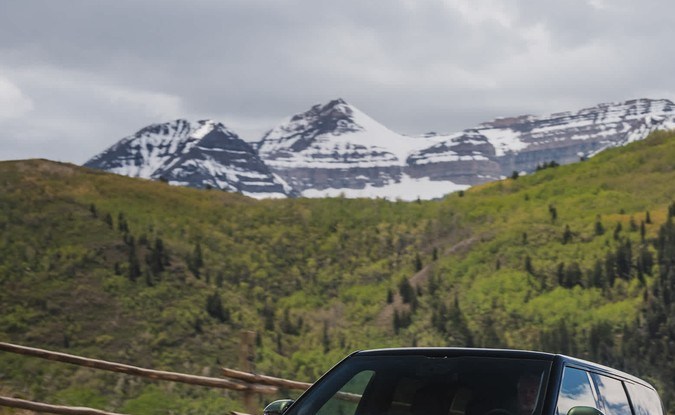 Dos Rivian R2, una verde oscuro y otra blanca, circulan por una carretera de montaña en Utah.