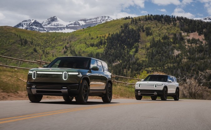 Dos Rivian R2, una verde oscuro y otra blanca, circulan por una carretera de montaña en Utah.