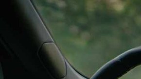 Interior de un Rivian R2 en marcha, con el conductor sin manos en el volante y la pantalla encendida.