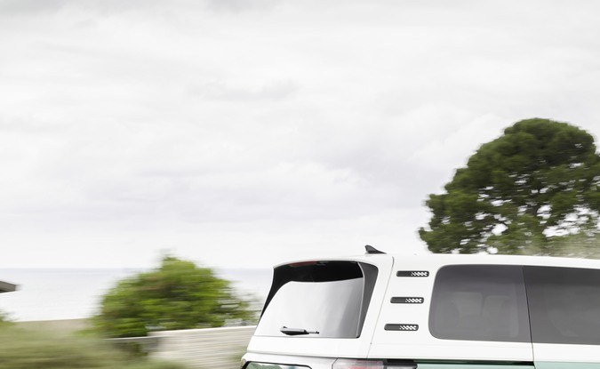 Parte trasera del Volkswagen ID. Buzz bitono verde y blanco en movimiento por una carretera