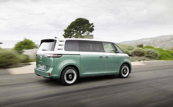 Parte trasera del Volkswagen ID. Buzz bitono verde y blanco en movimiento por una carretera